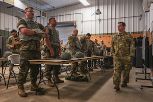 A group of people in uniform try on combat vests.