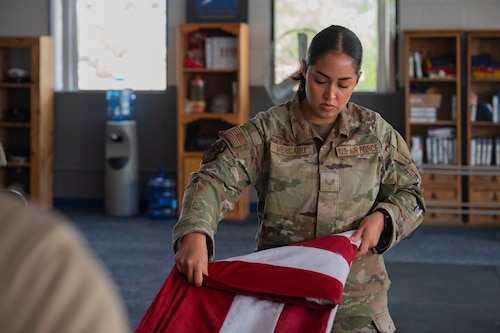 U.S. Air Force Senior Airman Melanie Mercado, an honor guardsman in training with the Davis-Monthan Air Force Base Honor Guard, practices the flag-folding technique at Davis-Monthan Air Force Base, Arizona, July 21, 2025. Used in funerals, retirements and memorials, the flag-folding technique embodies the core values of the USAF. (U.S. Air Force photo by Airman Samantha Melecio)