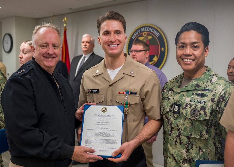 250415-N-IX644-1037 (April 15, 2025) FALLS CHURCH, Va. Chief, U.S. Navy Bureau of Medicine and Surgery Rear Adm. Darin Via, left, and Force Master Chief PatrickPaul Mangaran, director of the Hospital Corps, meritoriously promote Hospital Corpsman 3rd Class Alexander Brady to the rank of Petty Officer 2nd Class during an awards ceremony at Defense Health Headquarters, April 15. Brady was selected as the BUMED Fiscal Year 2024 Bluejacket of the Year. (U.S. Navy photo by Mass Communication Specialist 2nd Class Sasha Ambrose)