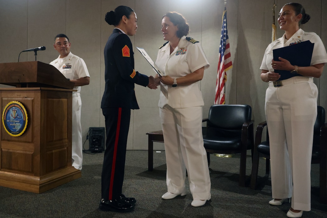 Philippine Marine Staff Sgt. Geraldine Corbita from Zamboanga, Philippines, shakes hands with Cmdr. Tuesday Adams, officer in charge of the Surface Warfare Medical Institute (SWMI), as she receives her Independent Duty Corpsman certificate of completion, July 11, 2025. Corbita is the first Philippine Navy Marine corpsman to graduate from the U.S. Navy IDC School, a milestone signaling a strengthened alliance between the U.S. and the Armed Forces of the Philippines (AFP). Senior Chief Hospital Corpsman Jami Erickson (right), acting SWMI senior enlisted leader, and Chief Hospital Corpsman Christian Lopez (left), IDC Class 24025 class advisor, look on during the graduation ceremony at the SWMI in San Diego,. (U.S. Navy photo by Arsenio R. Cortez Jr.)