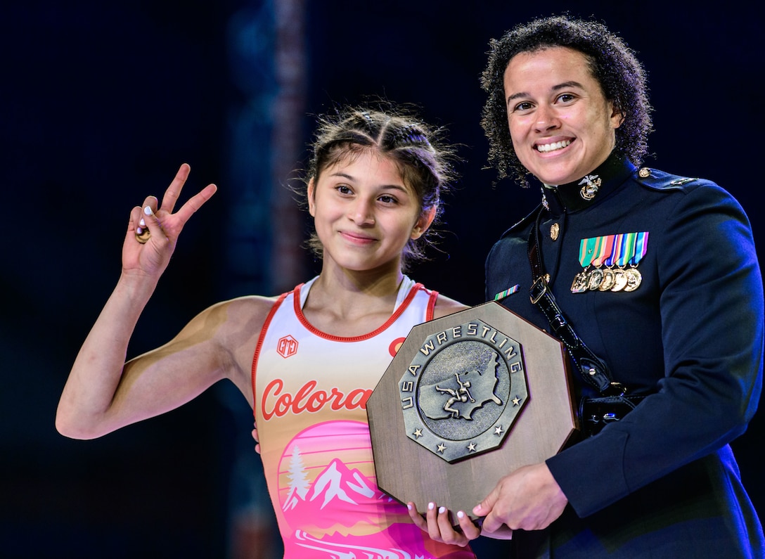 U.S. Marine Corps Capt. Monique Devitt, head of naval and enlisted programs with Marine Corps Recruiting Command, presents an award to a national champion during the 2025 U.S. Marine Corps Junior Nationals in Fargo, North Dakota July 13, 2025. The event hosts women’s and men’s freestyle and Greco-Roman competitions. This major event is the largest High School competition and is officially the largest wrestling tournament in the world. Approximately 8,760 athletes and coaches are expected to participate. (USA Wrestling photo by Tony Rotundo)