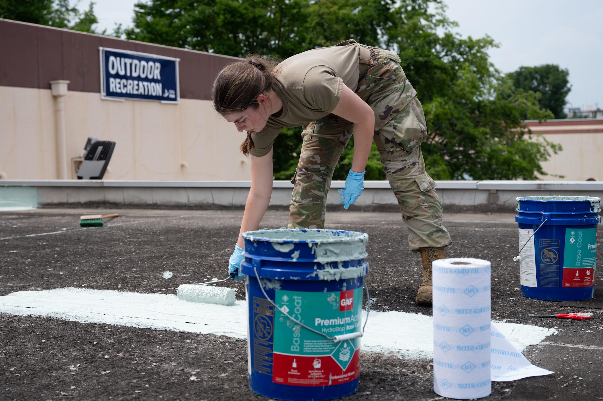 Airman rolls sealant onto a roof.