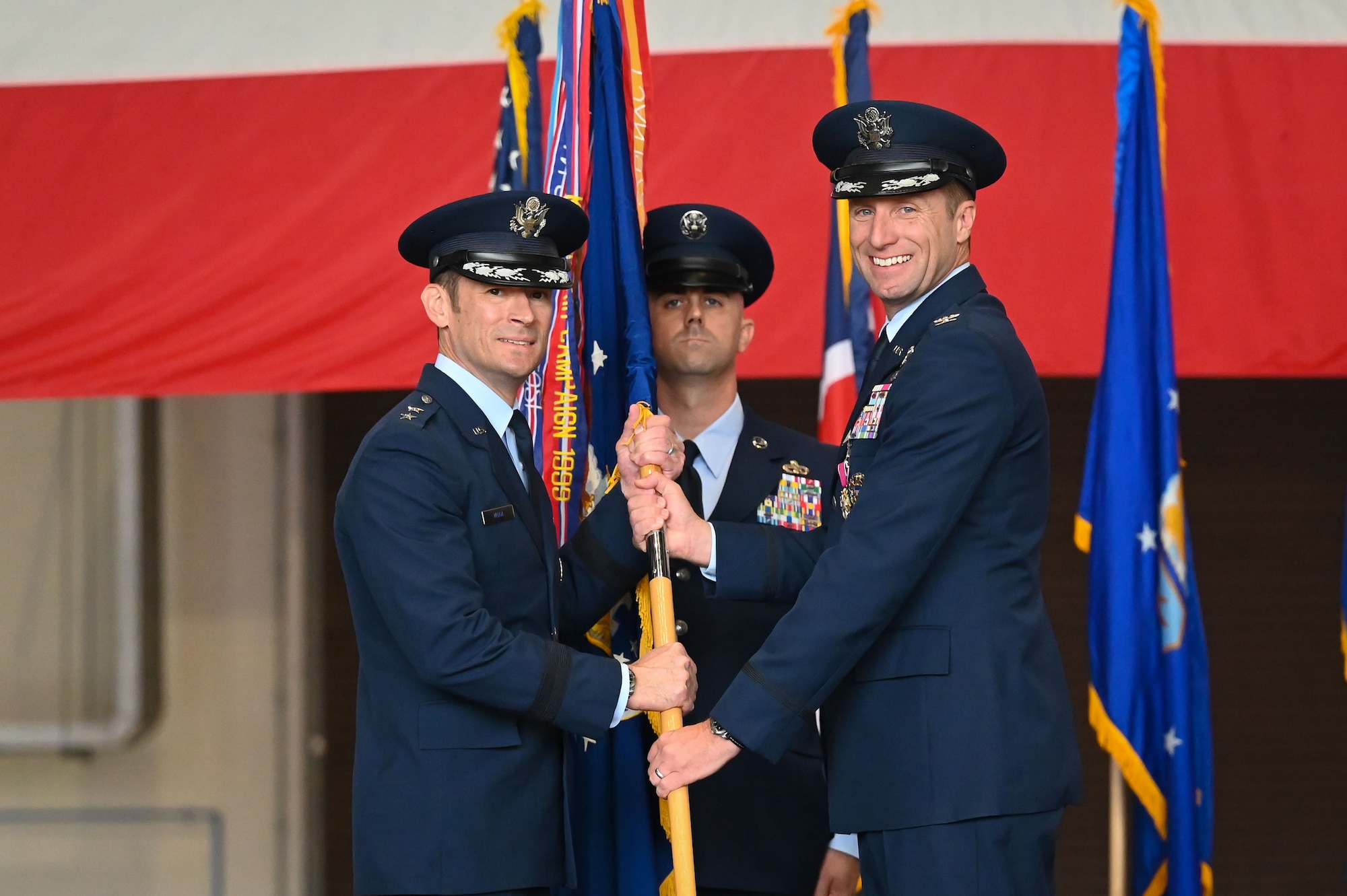 U.S. Air Force Col. Ryan Garlow, 100th Air Refueling Wing outgoing commander, passes the guidon on to Maj. Gen. Paul Moga, Third Air Force commander, during the 100th Air Refueling Wing change of command ceremony at RAF Mildenhall, England, July 22, 2025.