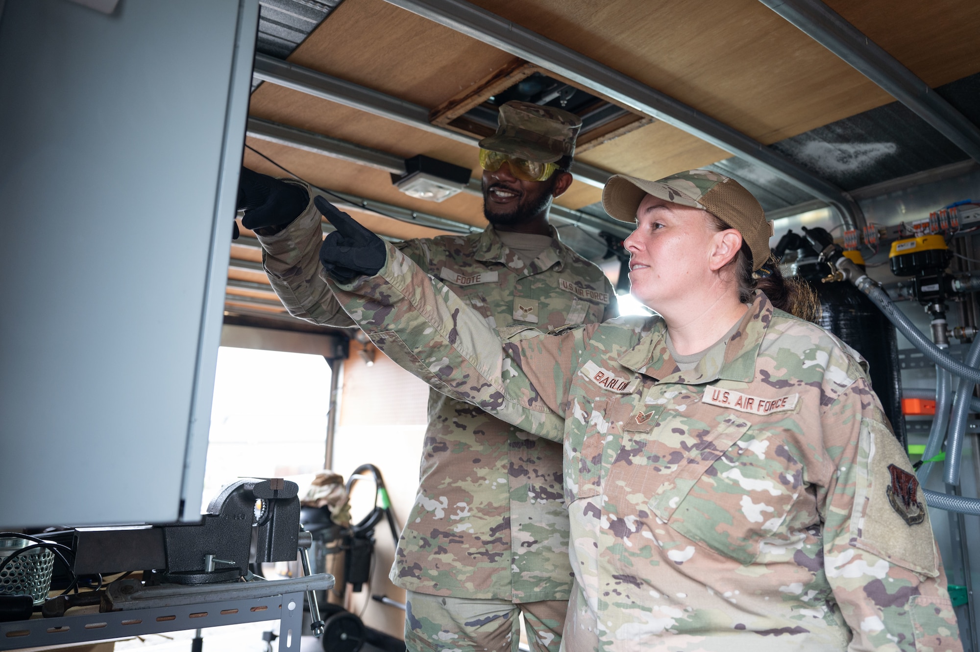 Airmen point at a monitor.