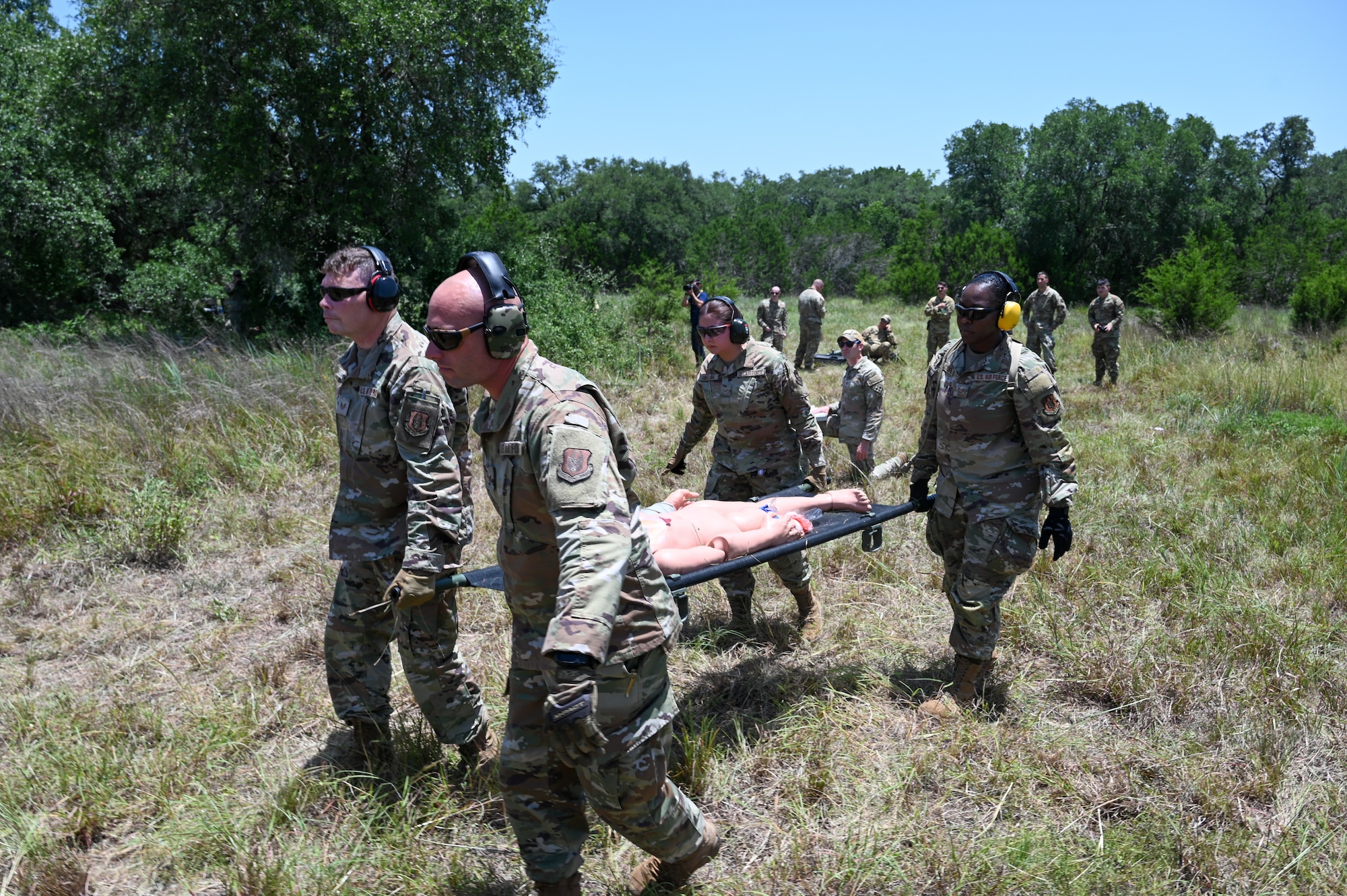 Senior Airman John Hall, center left, 26th Aerial Port Squadron aerial port specialist, helps with a litter carry alongside fellow Airmen during a simulated Army medevac during OPERATION DUSTOFF VIGILANCE ’25 at Joint Base San Antonio-Camp Bullis, Texas, July 16, 2025.