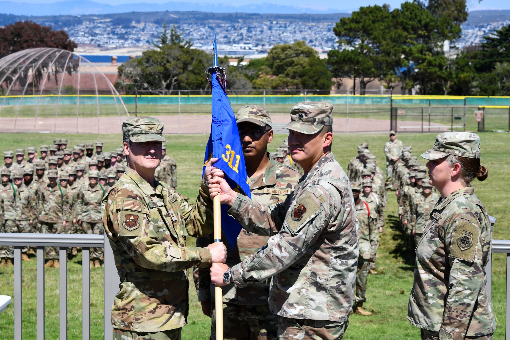 U.S. Air Force Col. Jason Guyette, 517th Training Group commander, takes the guidon from Lt. Col. Chin Tam, 311th Training Squadron outgoing commander, during the 311th TRS change of command ceremony on Soldier Field at Presidio of Monterey, California, July 18, 2025. The mission of the 311th Training Squadron is to develop world-class language-enabled warrior Airmen. (Courtesy photo)