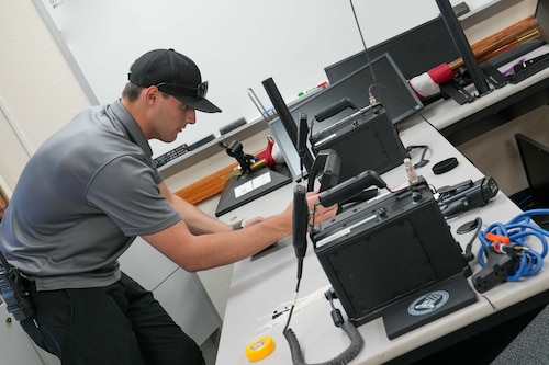 a man leans over a desk to look at communications equipment