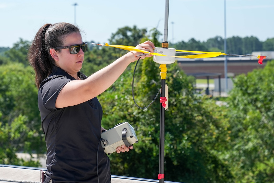 a woman in sunglasses adjusts a rooftop antenna