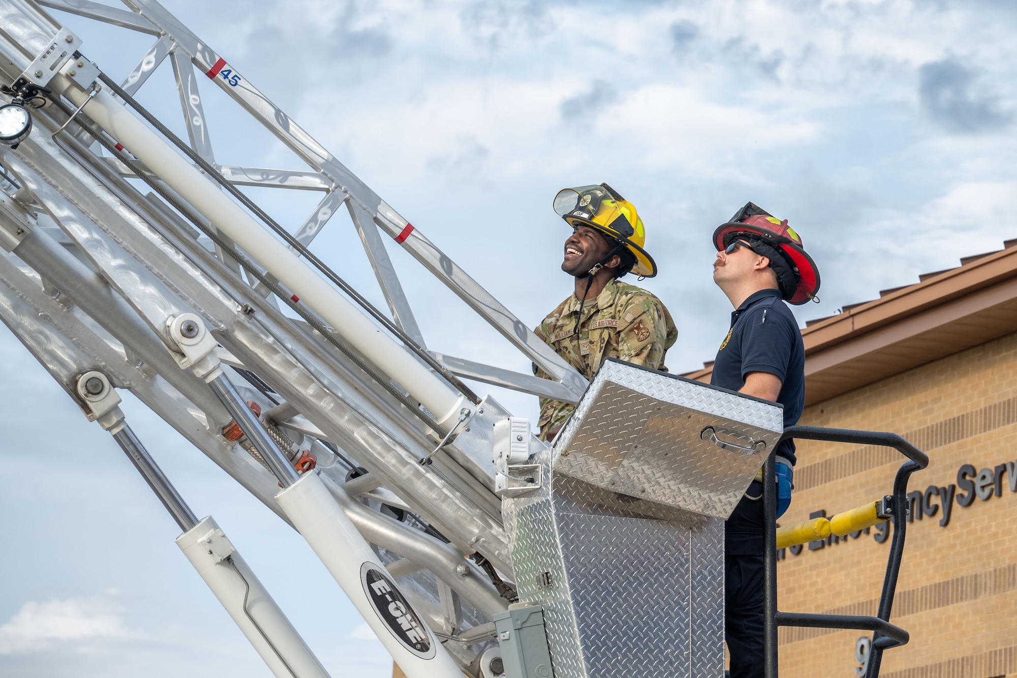 Airman 1st Class Joshua Williams, 22nd Civil Engineer Squadron firefighter, and fire Lt. Robert Griffin, 22nd CES driver operator, control a fire truck ladder at McConnell Air Force Base, Kansas, July 18, 2025. Personal protective equipment must be worn while controlling the fire truck ladder. (U.S. Air Force photo by Airman 1st Class Paula Arce)