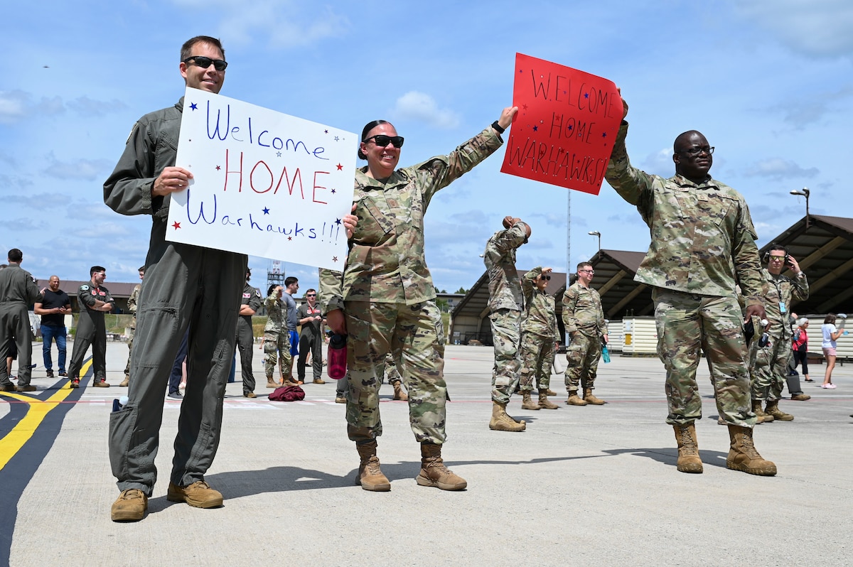 Airmen hold up welcome home signs.