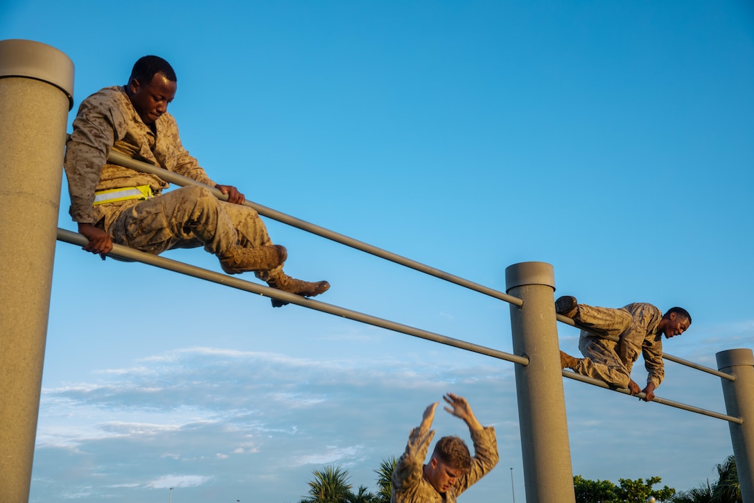U.S. Marines with 3rd Marine Logistics Group and 4th MLG traverse double bars during an obstacle course on Camp Kinser, Okinawa, Japan, July 17, 2025. The course is designed to challenge functional fitness and combat readiness. (U.S. Marine Corps photo by Cpl. Eric Allen)