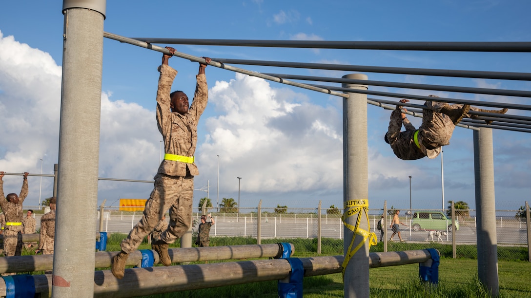 U.S. Marines with 3rd Marine Logistics Group and 4th MLG traverse incline bars during an obstacle course on Camp Kinser, Okinawa, Japan, July 17, 2025. The course is designed to challenge functional fitness and combat readiness. (U.S. Marine Corps photo by Cpl. Eric Allen)