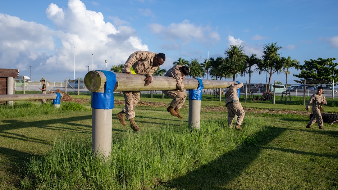 U.S. Marines with 3rd Marine Logistics Group and 4th MLG traverse high hurdles during an obstacle course on Camp Kinser, Okinawa, Japan, July 17, 2025. The course is designed to challenge functional fitness and combat readiness. (U.S. Marine Corps photo by Cpl. Eric Allen)