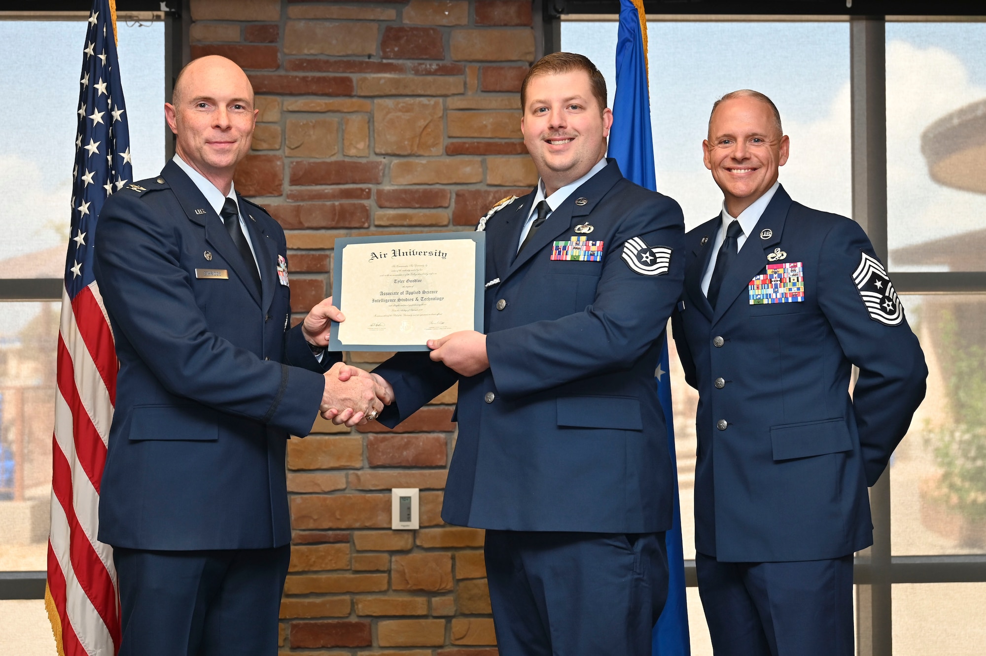 U.S. Air Force Tech. Sgt. Tyler Goodloe of the 7th Air Support Operations Squadron, Community College of the Air Force Graduate, center, accepts an Associate of Applied Science Degree from U.S. Air Force Col. John Ethridge, 49th Wing commander, left, and U.S. Air Force Chief Master Sgt. William Ford, 49th Wing command chief, during the graduation of CCAF at Holloman Air Force Base, New Mexico, July 11, 2025. Each enlisted Airman has the opportunity to earn a career-focused associate degree through the CCAF, empowering them to grow professionally while supporting the mission. (U.S. Air Force photo by Senior Airman Michelle Ferrari)