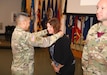 Col. Joselito “Joe” Lim, commander of the U.S. Army Medical Materiel Agency, places the silver medallion signifying membership in the Order of Military Medical Merit over the head of Kim Dankulich during an induction ceremony July 17 at Fort Detrick, Maryland.