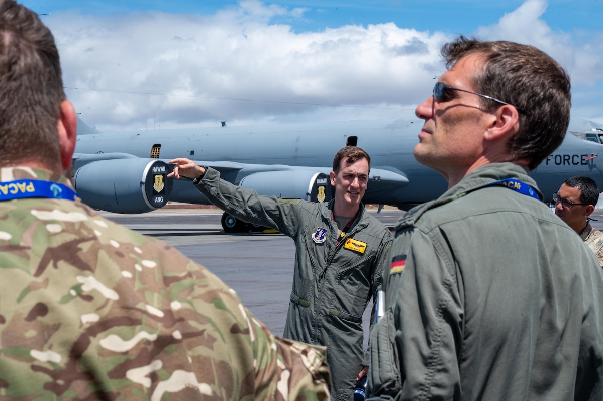 U.S. Hawaii Air National Guard Maj. Andrews Marchi (center), 199th Fighter Squadron F-22 Raptor pilot, speaks to multinational partners during an International Observer Program event on Joint Base Pearl Harbor-Hickam, Hawaii, July 18, 2025. The IOP event provided the international partner delegates with insight on how they could integrate into a future Resolute Force Pacific iteration, in an effort to encourage heightened efforts in maintaining security and stability in the Indo-Pacific. (U.S. Air Force photo by Senior Airman Mark Sulaica)