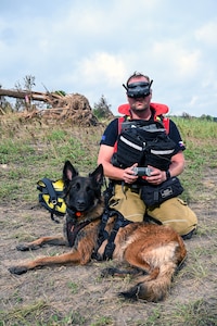 Jiri Studnicka, a drone operator with a Czech Republic emergency response team, or CZERT, kneels beside search-and-rescue dog Origami while operating a small drone along the Guadalupe River near Kerrville, Texas, July 15, 2025.
