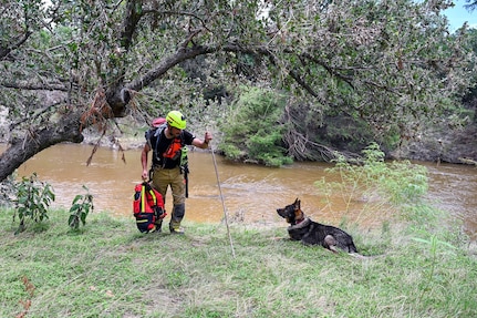 Matej Bartosik, a search and rescue dog handler with the Czech Republic's emergency response team, CZERT, works alongside his search-and-rescue dog, Bart, during flood response operations near Sisterdale, Texas, on July 18, 2025.