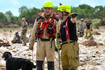 Petr Klega, left, a dog handler with the Czech Republic's emergency response team, or CZERT, talks with another team member while participating in search operations along the Guadalupe River near Sisterdale, Texas, on July 18, 2025. The Czech team conducted operations in tandem with Texas Army National Guard members as part of flood response efforts.