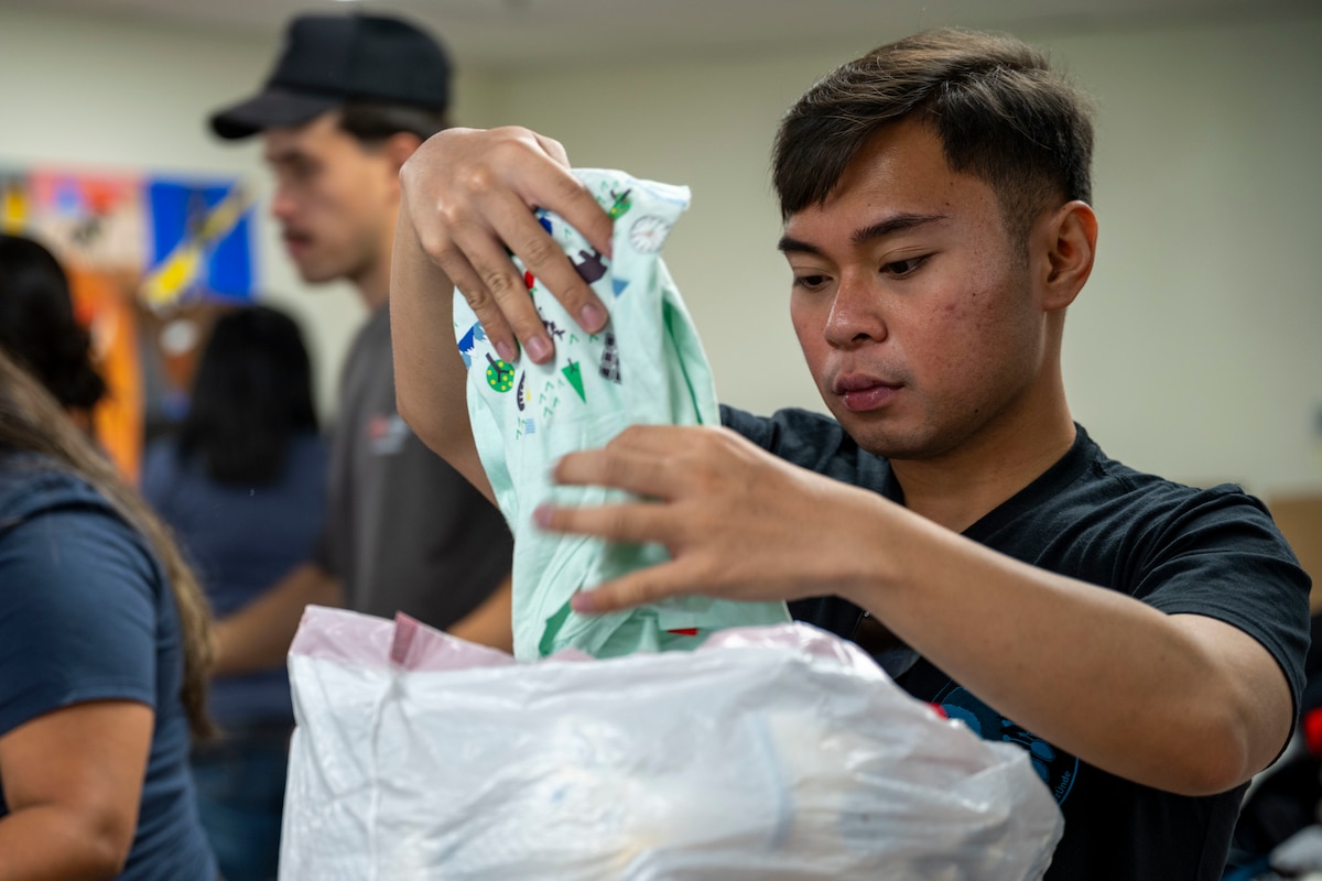 U.S. Air Force Senior Airman Davide Bumagat, 29th Attack Squadron aviation resource management journeyman, helps sort through clothing donations at Mescalero, New Mexico, July 19, 2025.