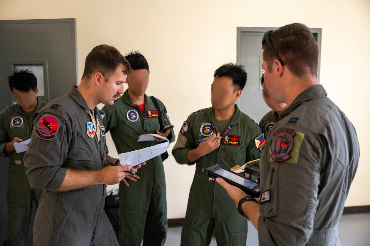 U.S. Air Force Capt. Tyler Rico (2nd left) and Capt. Toney Fisher (right), 421st Mission Generation Force Element F-35A pilots, coordinate flight plans with Philippine Air Force pilots during the Cope Thunder 25-2 exercise at Clark Air Base, Philippines, July 7, 2025. The training conducted between the U.S. and Philippine Air Force strengthens both the ability to respond together for potential future crises, contingencies and natural disasters. (U.S. Air Force photo by Airman 1st Class Aden Brown) (Image blurred for operational security)