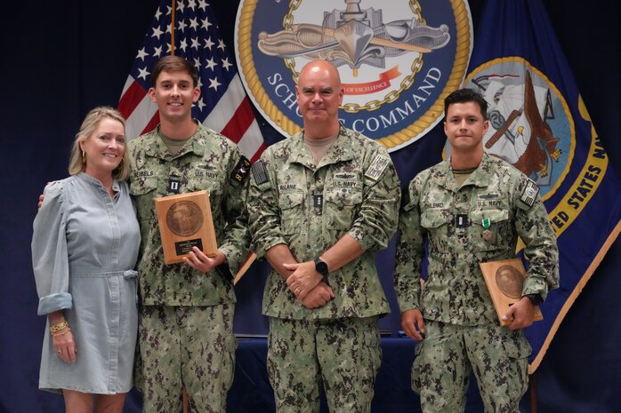 Vice Adm. Brendan McLane, commander, Naval Surface Force, U.S. Pacific Fleet, stands with Lt. Potter Seibels, winner of the Shiphandler of the Year Award, and his mother, Hallie Seibels (left), and L.t. j.g. Jake Chalenko (right), runner up in the Shiphandler of the Year Award, Surface Warfare Schools Command headquarters, Naval Station Newport, R.I., July 15, 2025.