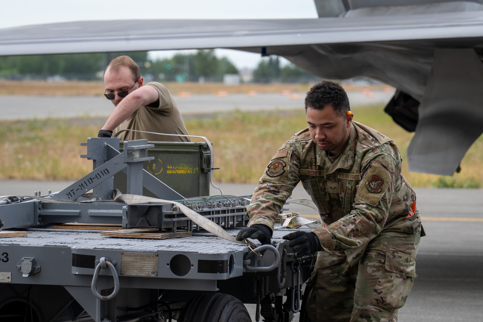 U.S. Air Force Senior Airman Joshua Rowan (left), and Senior Airman Brent Scheib (right),  munitions build crew members assigned to the 3rd Munitions Squadron, begin to assemble munitions during the second quarter mission generation competition at Joint Base Elmendorf-Richardson, Alaska, July 18, 2025.