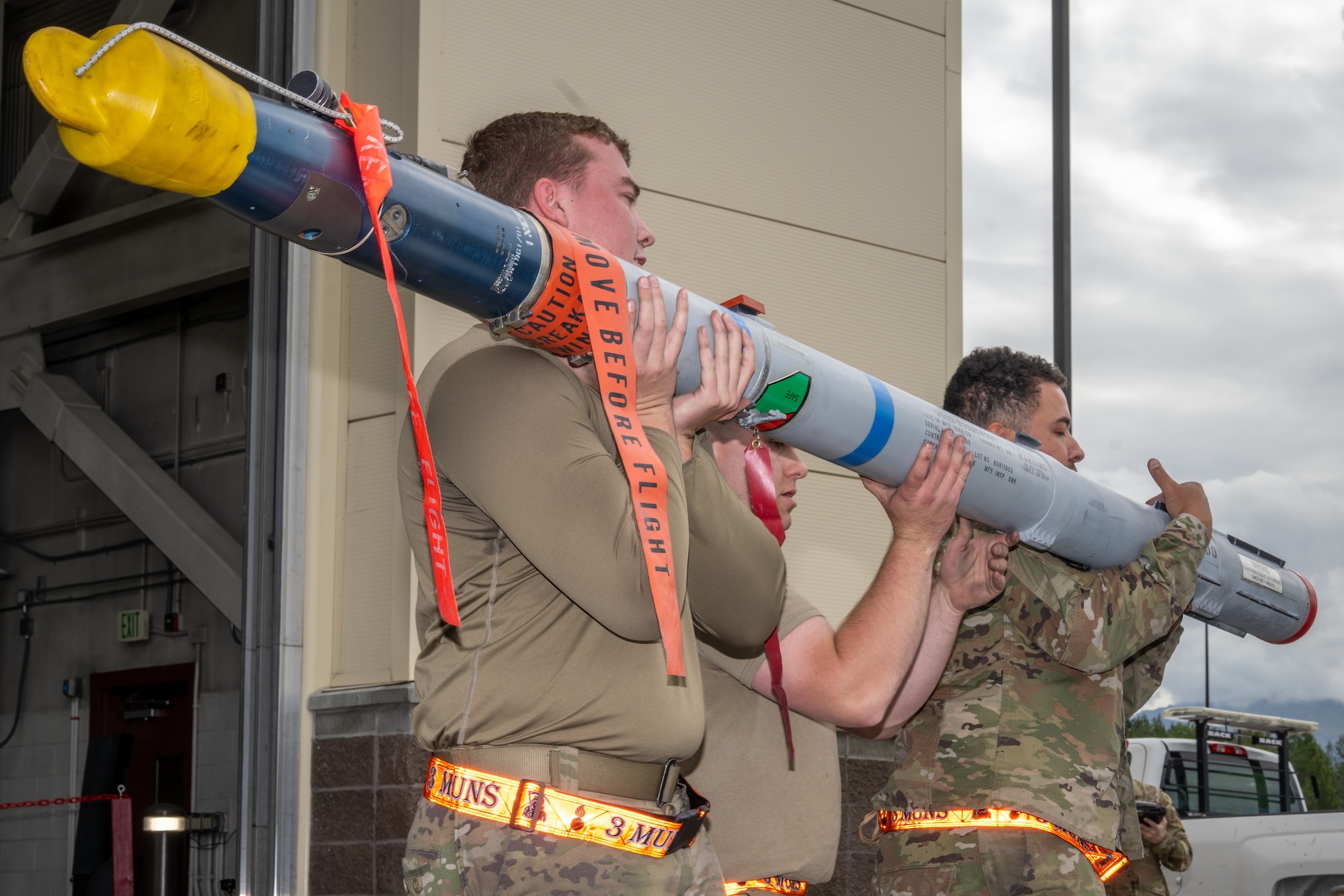 From left, U.S. Air Force Senior Airman Skyler Morris, Senior Airman Gordon Buchwitz and Senior Airman Brent Scheib, munitions build crew members assigned to the 3rd Munitions Squadron carry munitions to a loading platform during the second quarter mission generation competition at Joint Base Elmendorf-Richardson, Alaska, July 18, 2025.