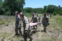 Senior Airman John Hall, center left, 26th Aerial Port Squadron aerial port specialist, helps with a litter carry alongside fellow Airmen during a simulated Army medevac during OPERATION DUSTOFF VIGILANCE ’25 at Joint Base San Antonio-Camp Bullis, Texas, July 16, 2025.