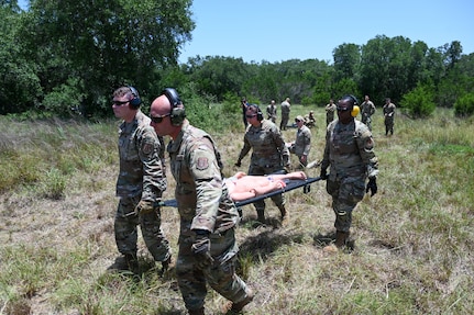 Senior Airman John Hall, center left, 26th Aerial Port Squadron aerial port specialist, helps with a litter carry alongside fellow Airmen during a simulated Army medevac during OPERATION DUSTOFF VIGILANCE ’25 at Joint Base San Antonio-Camp Bullis, Texas, July 16, 2025.