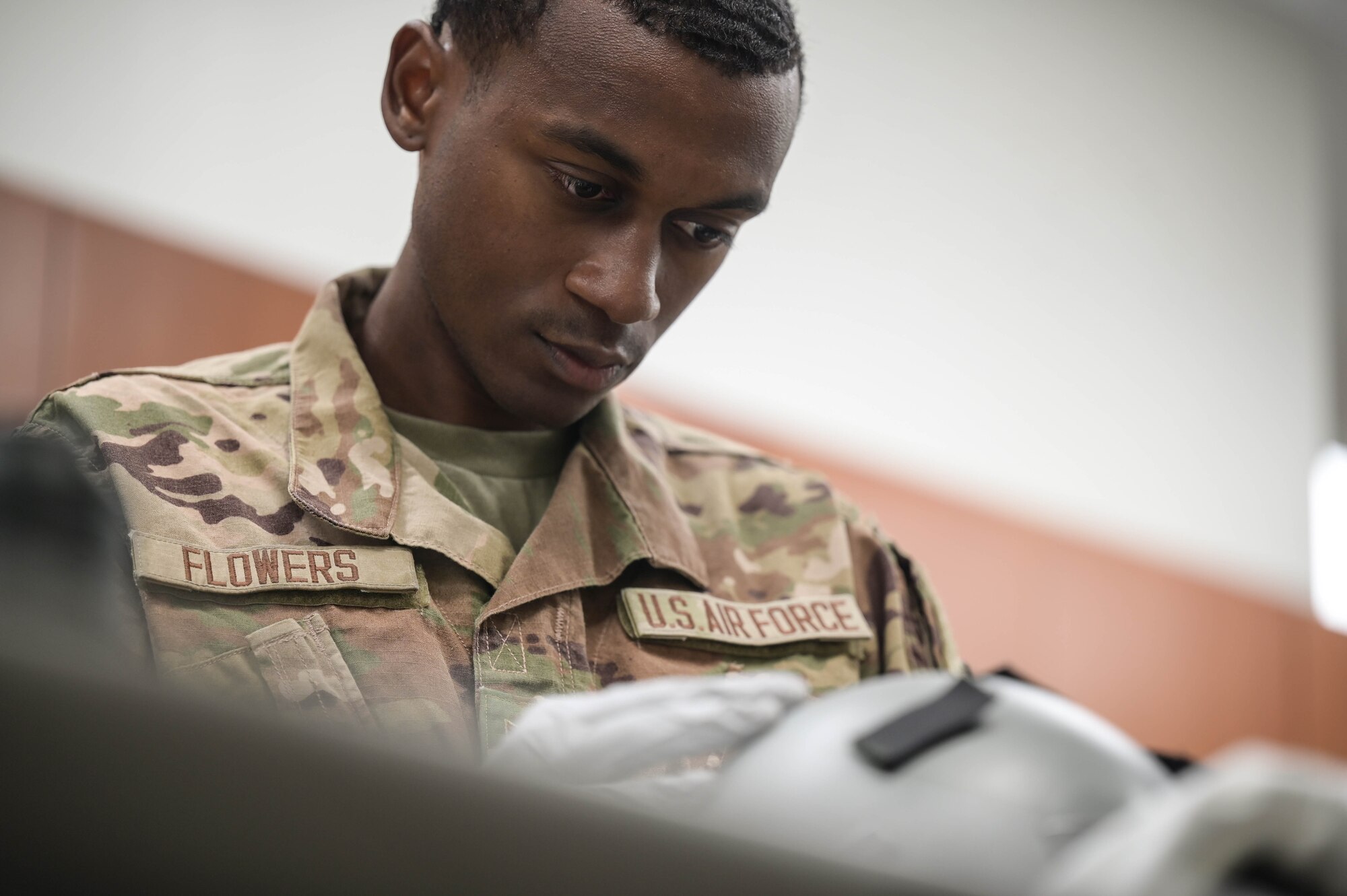 A close-up shot of an Airman visually inspecting a pilot's helmet.