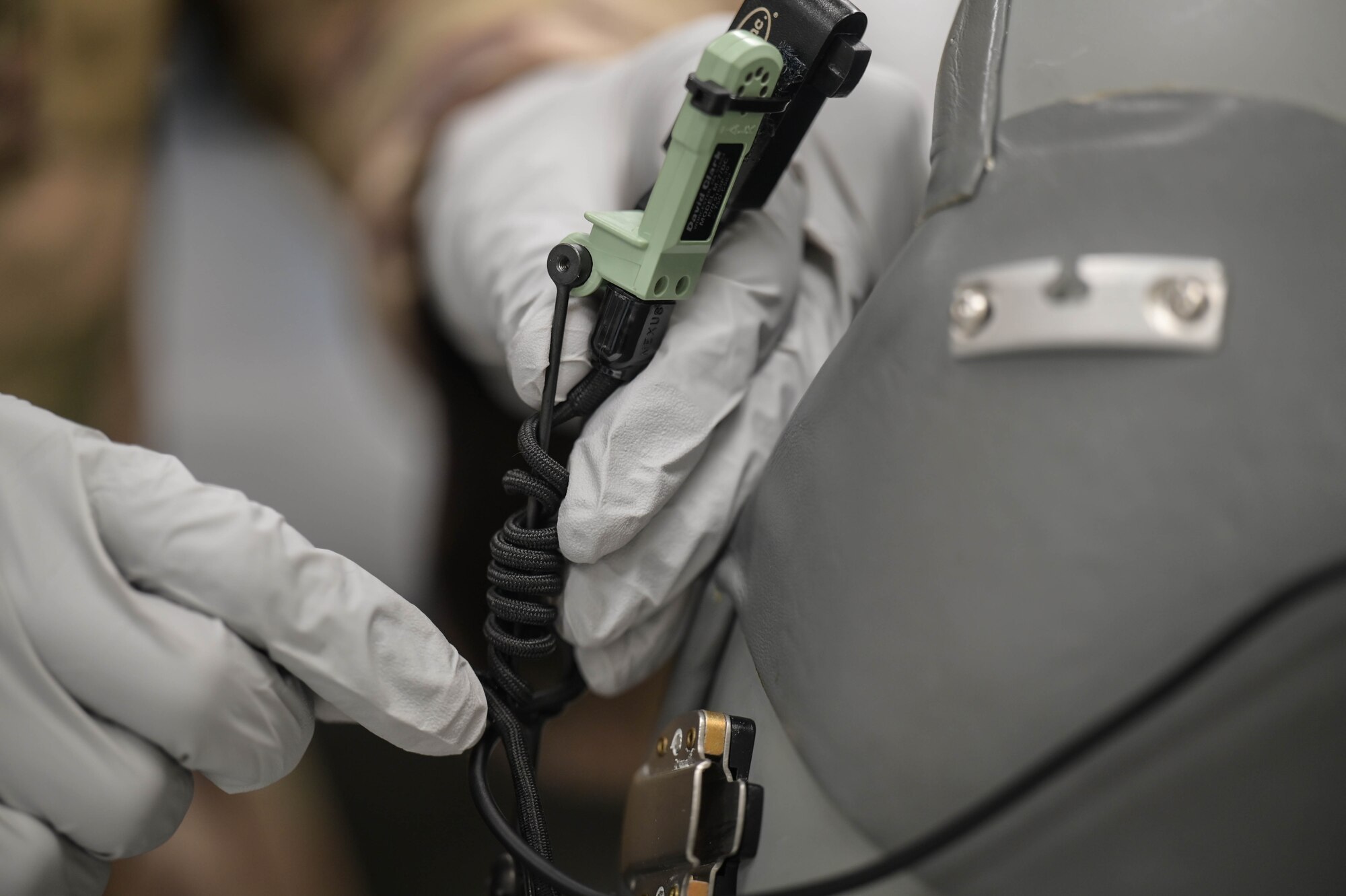 Two large, gloved hands manipulate a pilot's mic on a helmet.