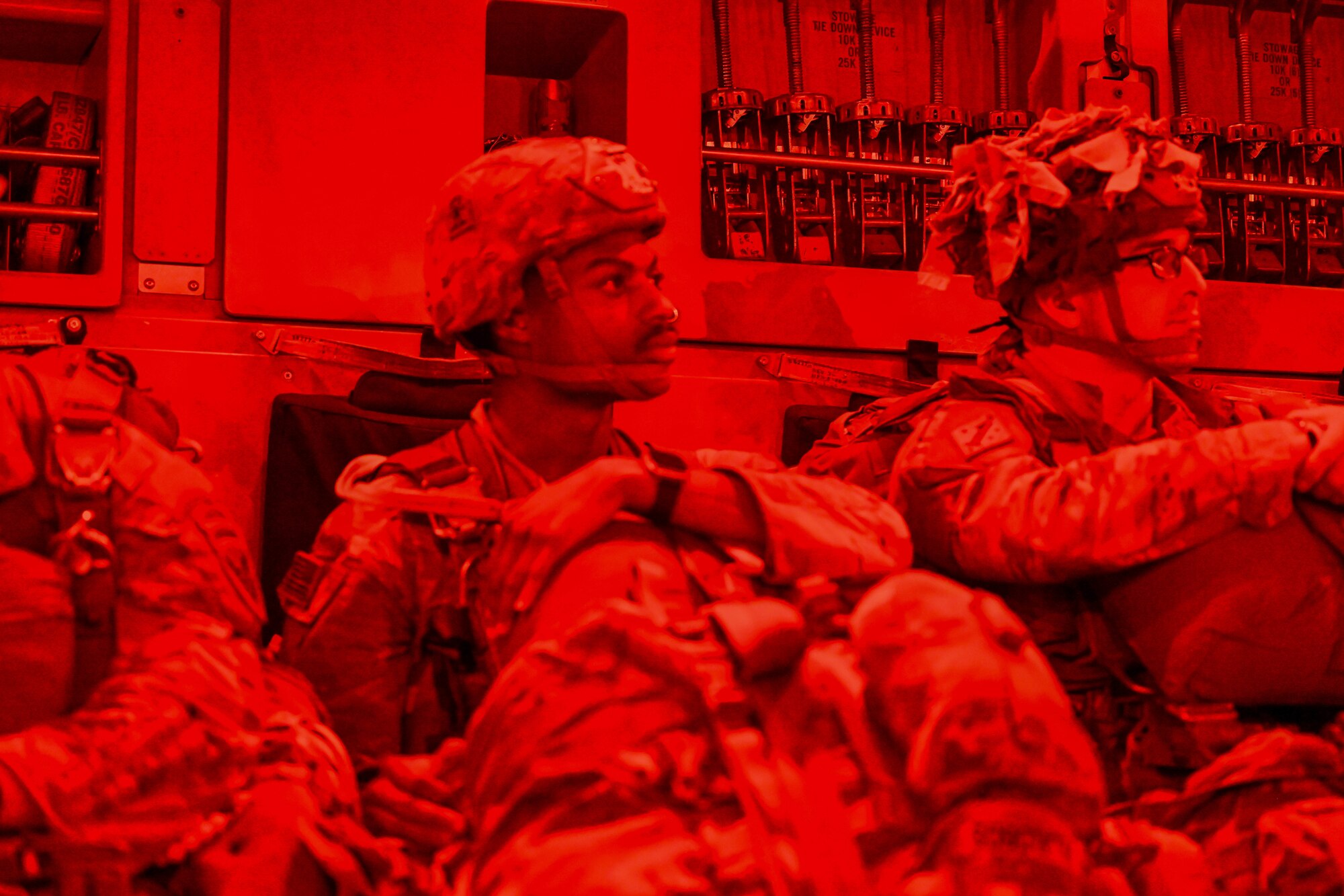 Airmen sit in a C-17 fuselage in all red photo.