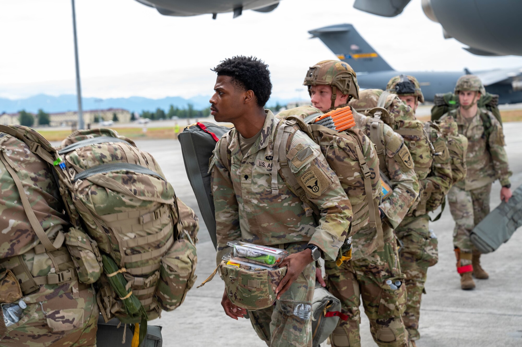 Soldiers line up on a flightline entering a C-17.