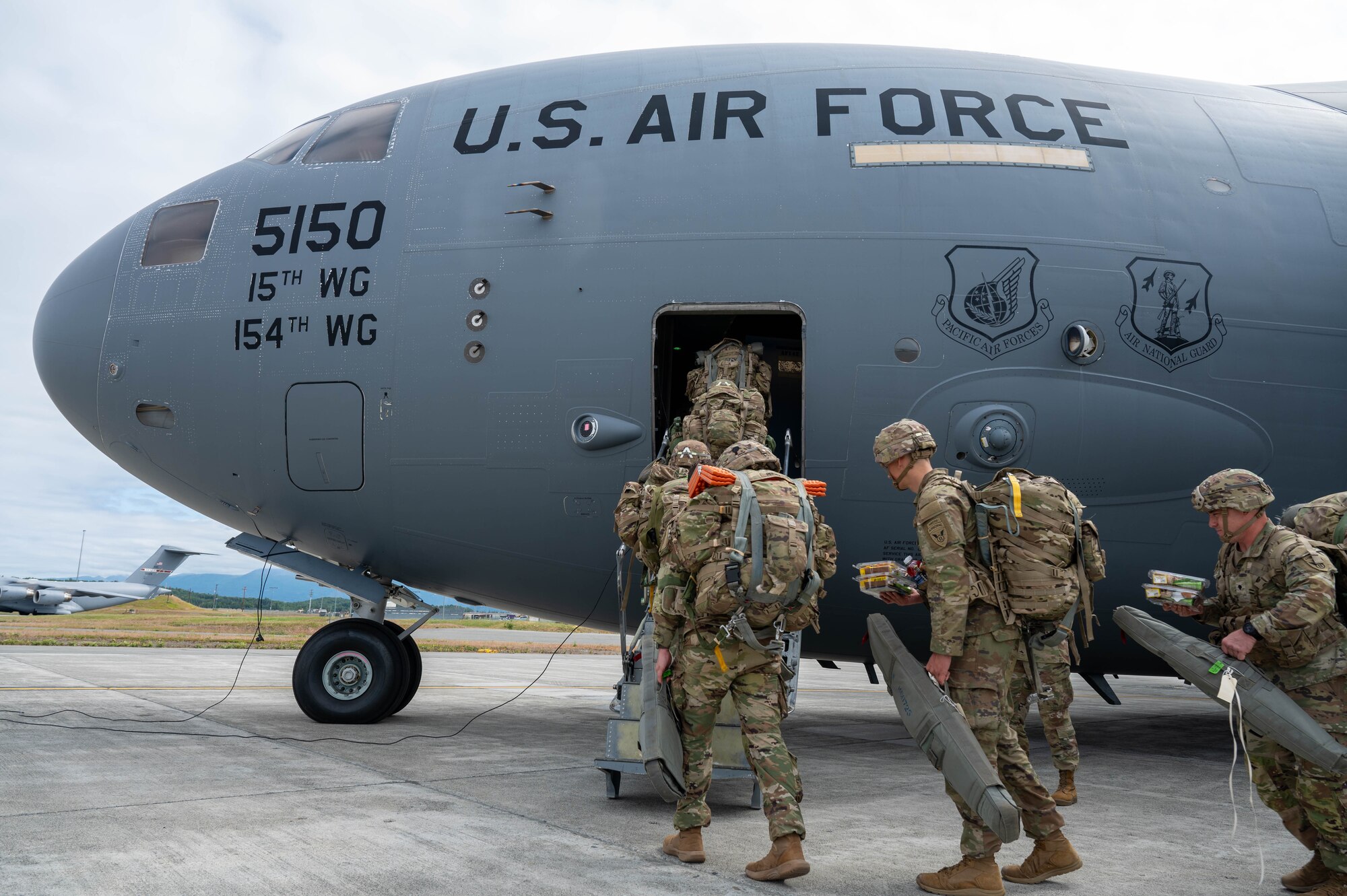 A line of soldiers enters a C-17 from the side door.