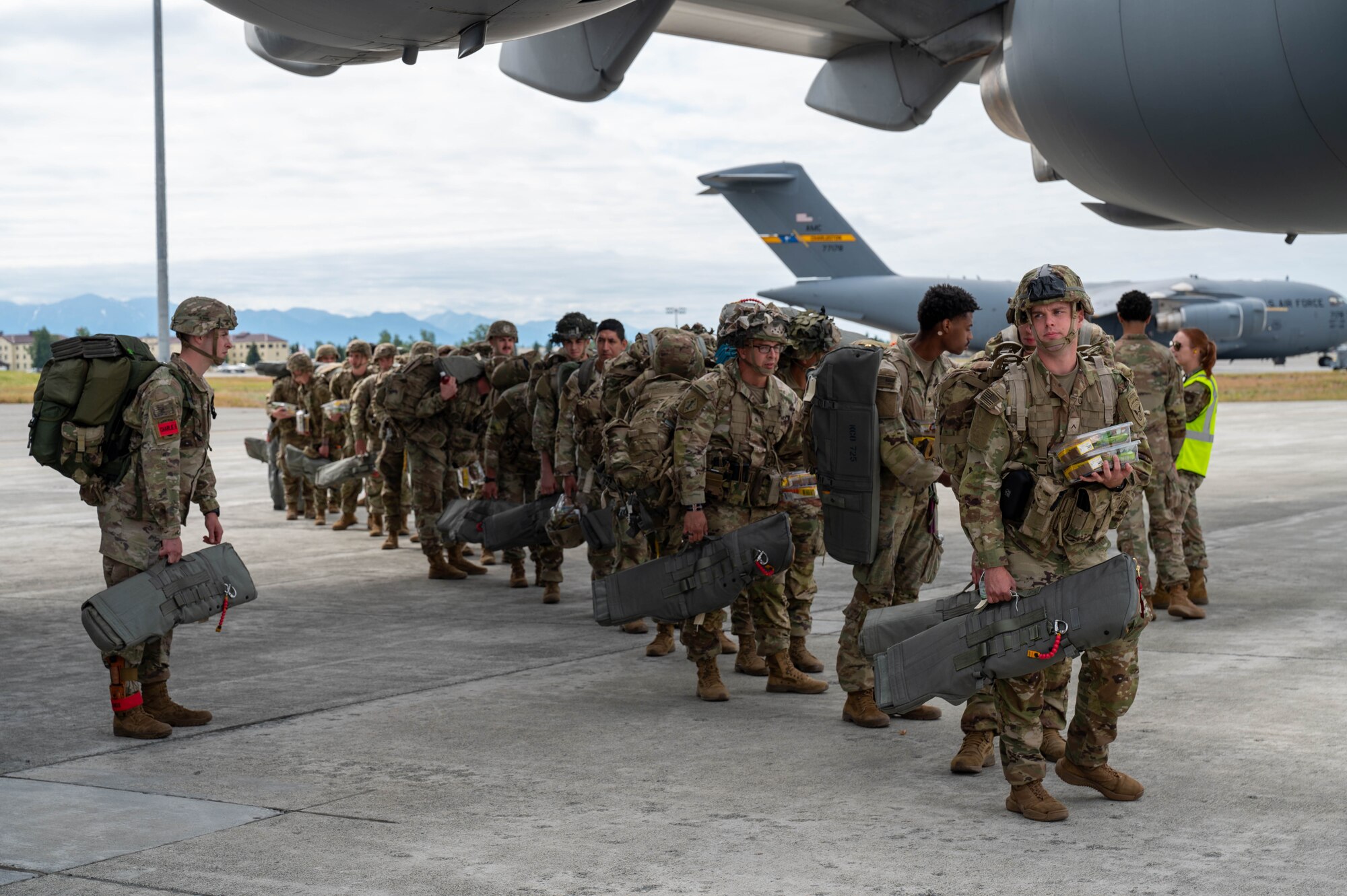 Soldiers standing in formation under the wing of a C-17.