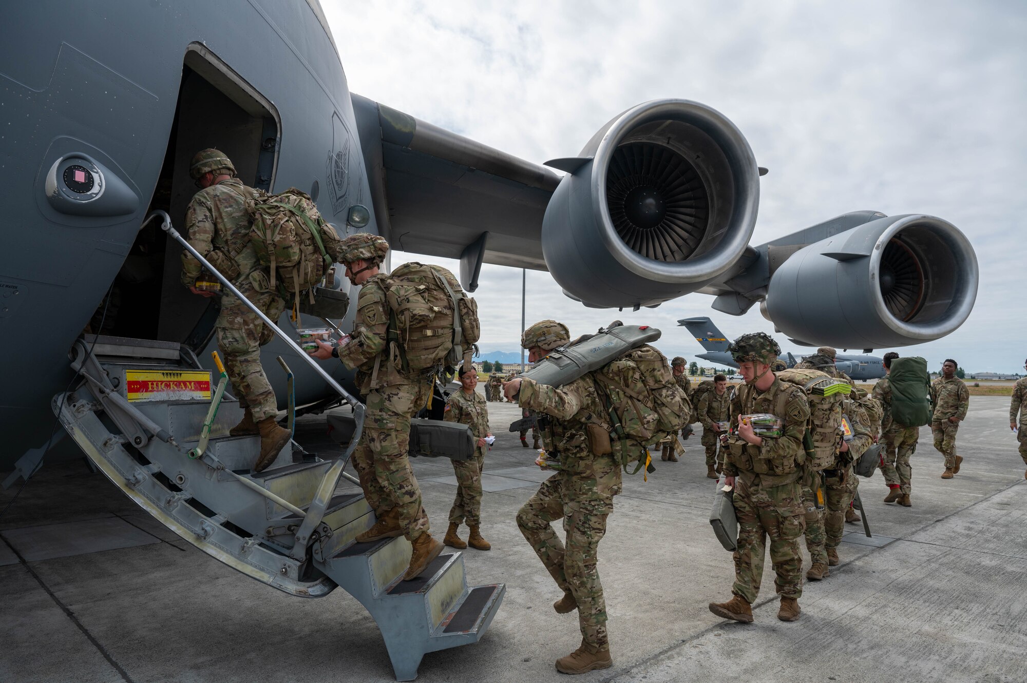 Soldiers enter a C-17 from a side door.