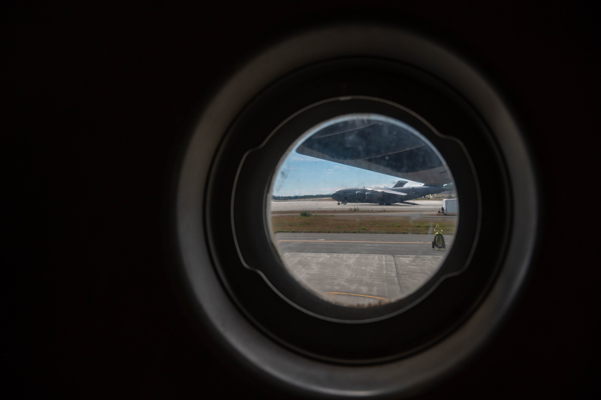 An aircraft pictured in a circle frame of a window on a C-17.