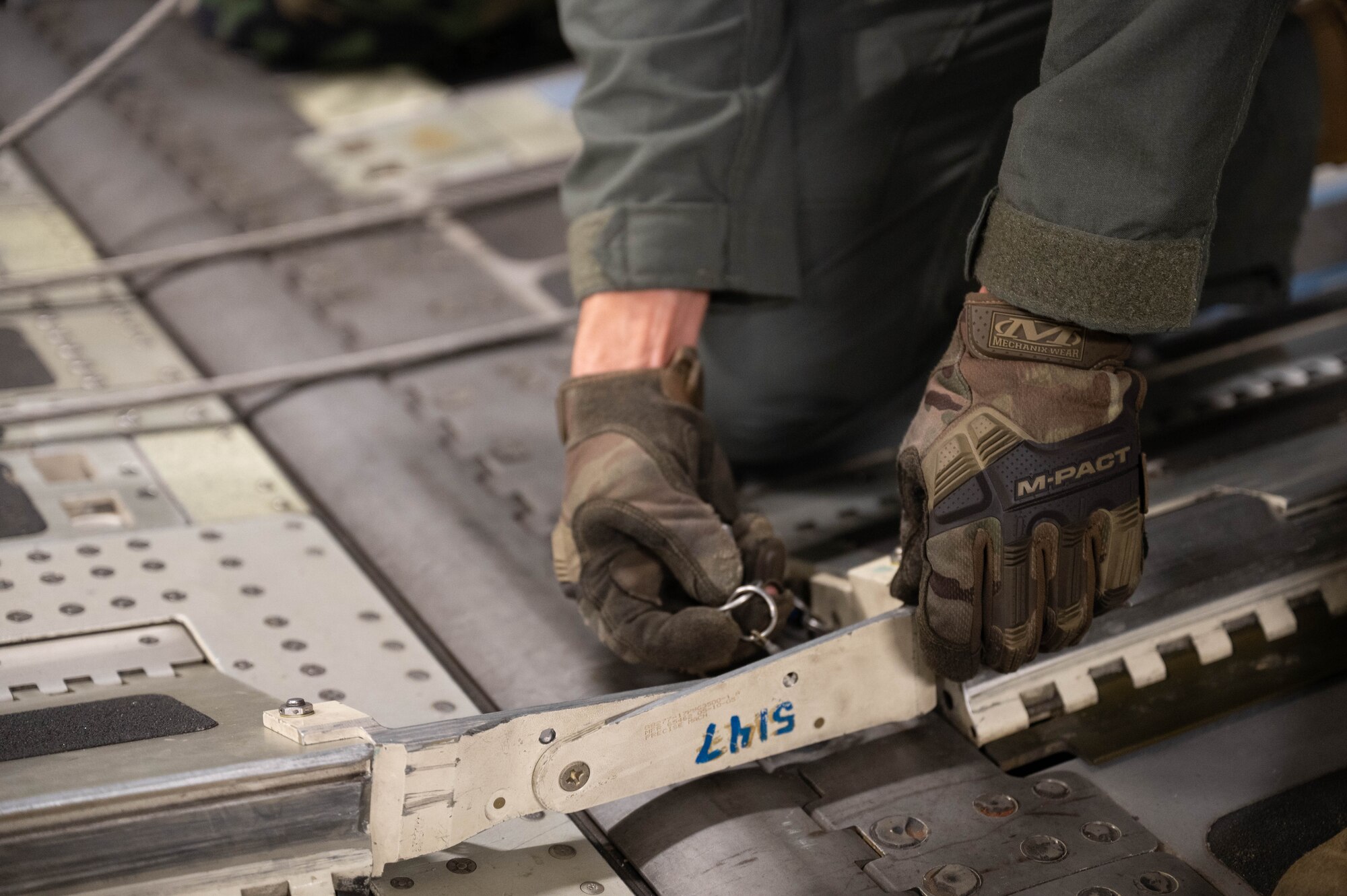Close up of a C-17 Globemaster's hands securing a pin onto a C-17.