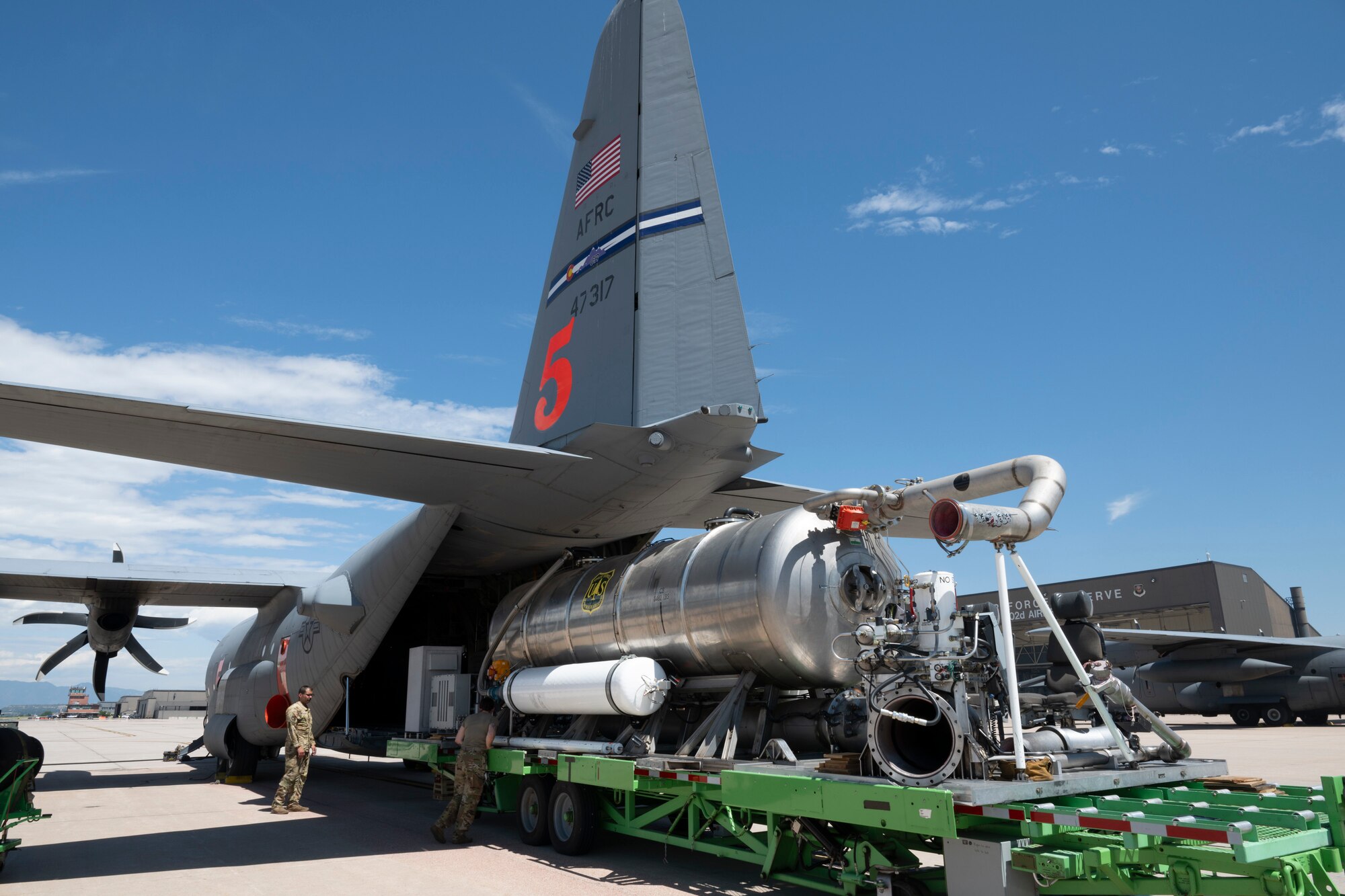 A large reservoir being loaded into the cargo bay of a military aircraft.