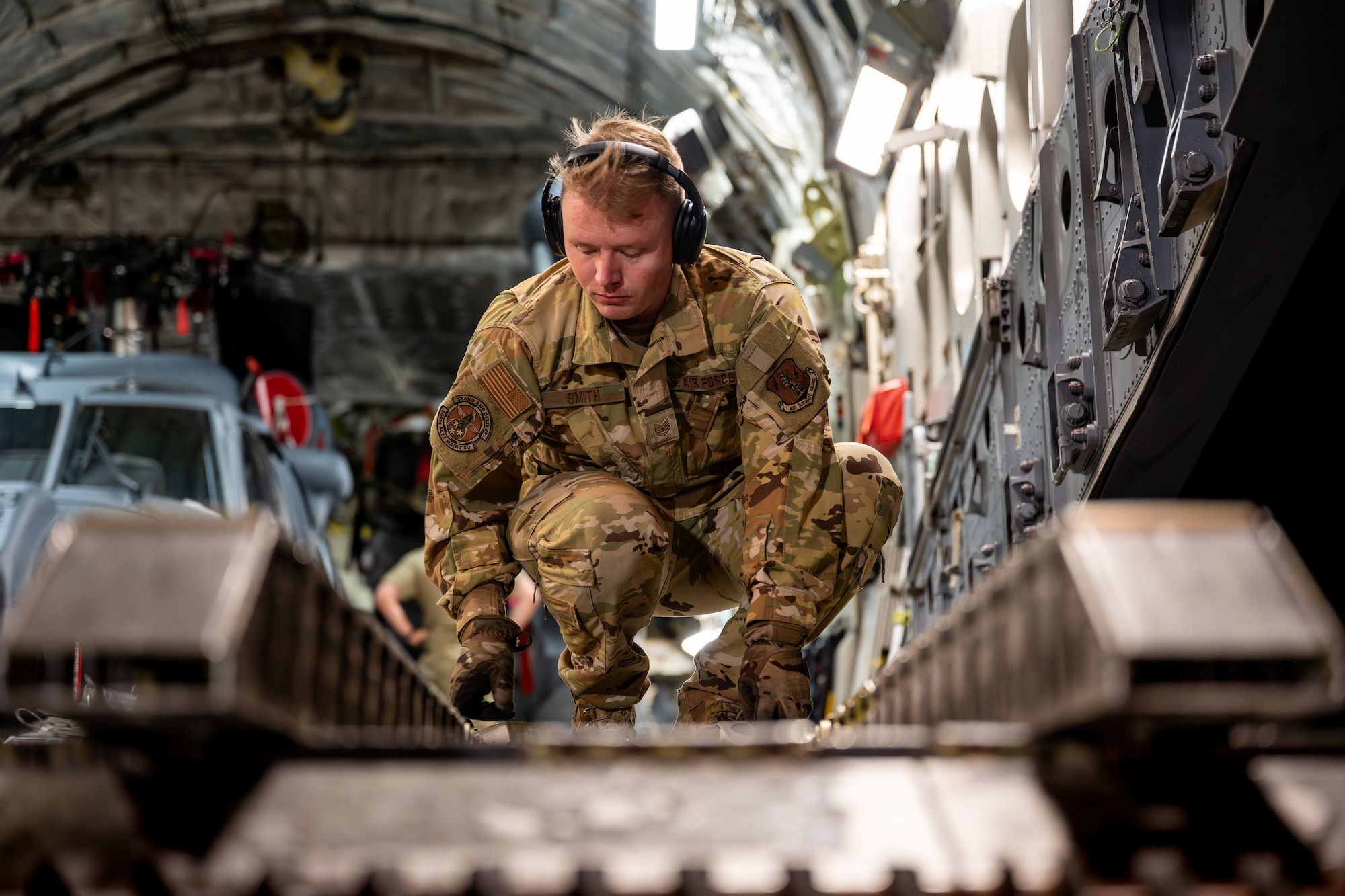 U.S. Air Force Staff Sgt. Joseph Smith, 164th Airlift Wing flying crew chief, adjusts cargo rollers after unloading cargo in support of exercise Resolute Force Pacific (REFORPAC) 2025