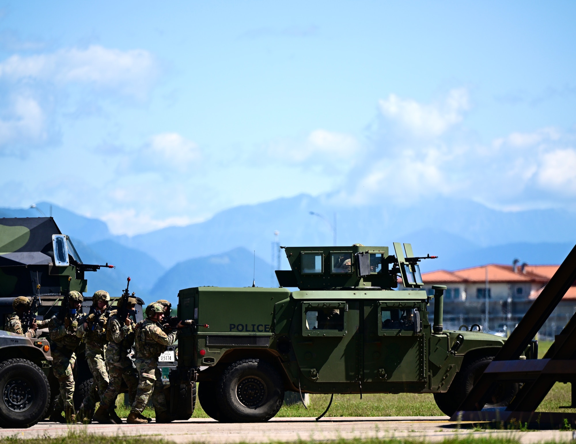 Airmen follow behind a military vehicle approaching the enemy.