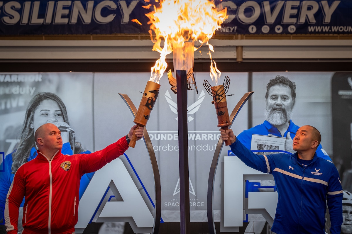 Image of two service members lighting a torch.