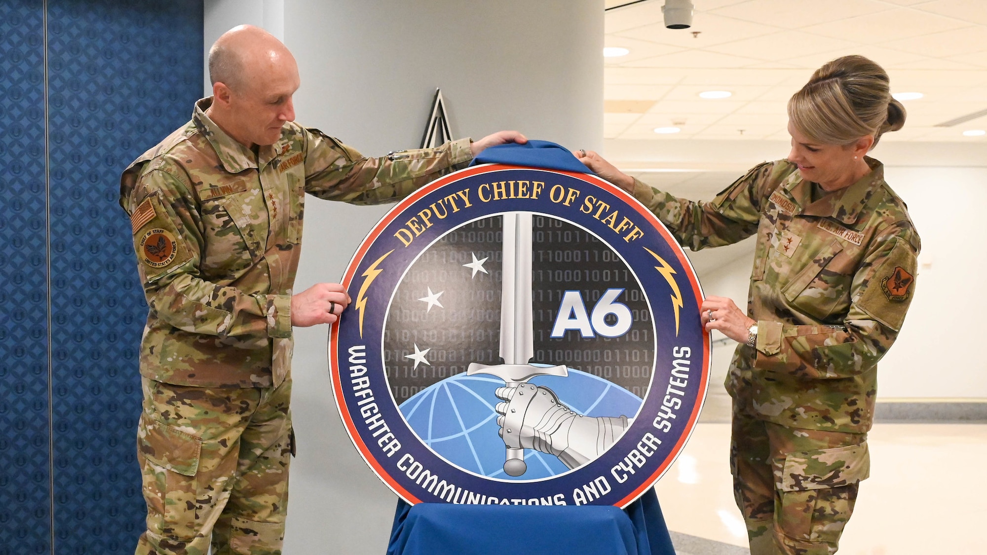 Two service members uncover the new logo.