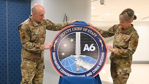 Two service members uncover the new logo.