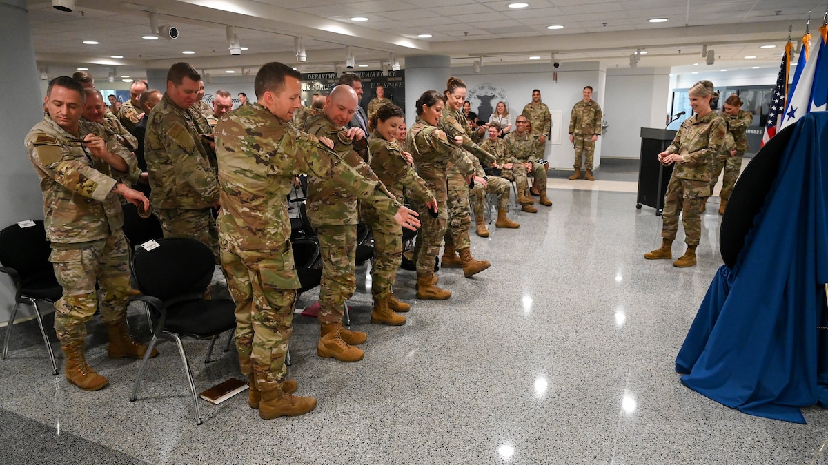Service members stand and replace their patches with new ones.