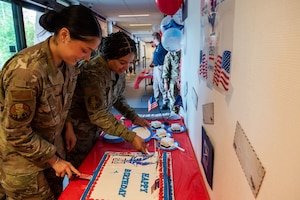 U.S. Air Force Airmen assigned to the 786th Force Support Squadron cut a cake for the United States Postal Service 250 year celebration at Ramstein Air Base, Germany, July 23, 2025. The USPS has been connecting service members and their families through mail for 250 years. (U.S. Air Force photo by Airman 1st Class Joseph Curzi)
