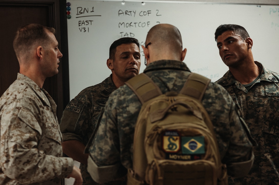 Corpo de Fuzileiros Navais (Brazilian Marine Corps ) marines observe U.S. Marines with Tactical Training and Exercise Control Group, Marine Air Ground Task Force Training Command, Marine Corps Air Ground Combat Center, as they operate a Fire Support Team Exercise during  Service Level Training Exercise 4-25 on Camp Wilson, Twentynine Palms, California, July 17, 2025. The Brazilian Marines were part of a delegation that visited to observe the SLTE process, designed, enabled, and overseen by the Tactical Training and Exercise Control Group, in order to improve their own standard operating procedures and increase operability with their U.S. partners. (U.S. Marine Corps photo by LCpl Dominic Spence)