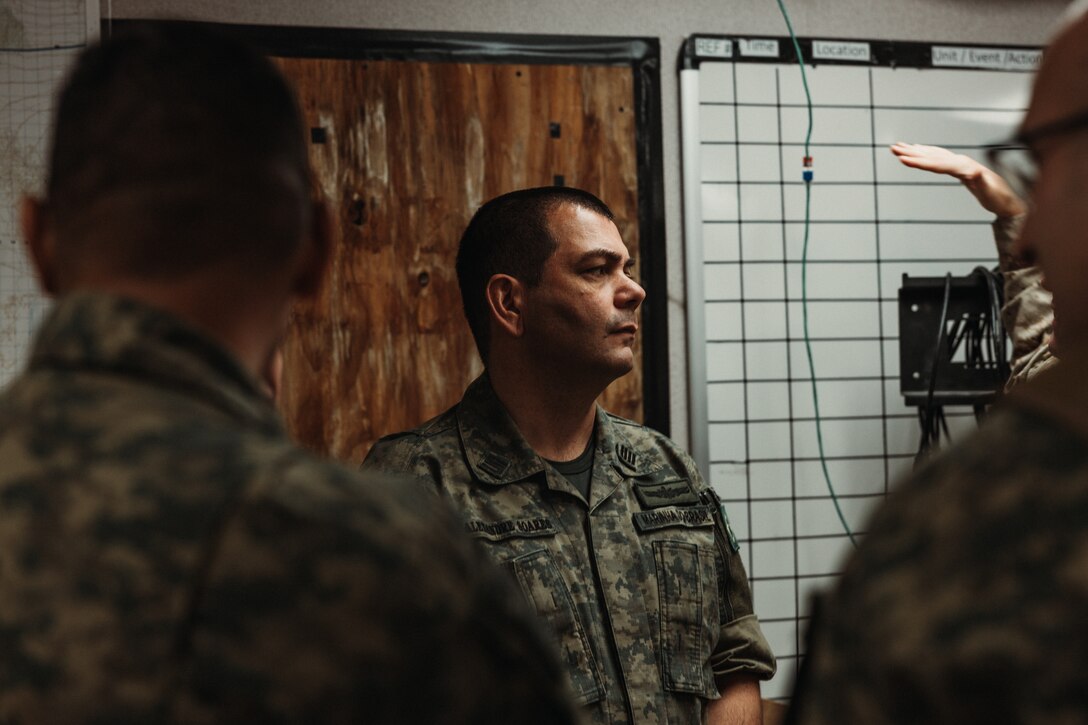 Capitão de mar e guerra (Brazilian colonel) Alexandre Soares de Arajo observes U.S. Marines with Tactical Training and Exercise Control Group, Marine Air Ground Task Force Training Command, Marine Corps Air Ground Combat Center, in the process of a Fire Support Team Exercise during Service Level Training Exercise 4-25 on Camp Wilson, Twentynine Palms, California, July 17, 2025. The Brazilian Marines were part of a delegation that visited to observe the SLTE process, designed, enabled, and overseen by the Tactical Training and Exercise Control Group, in order to improve their own standard operating procedures and increase operability with their U.S. partners. (U.S. Marine Corps photo by LCpl Dominic Spence)