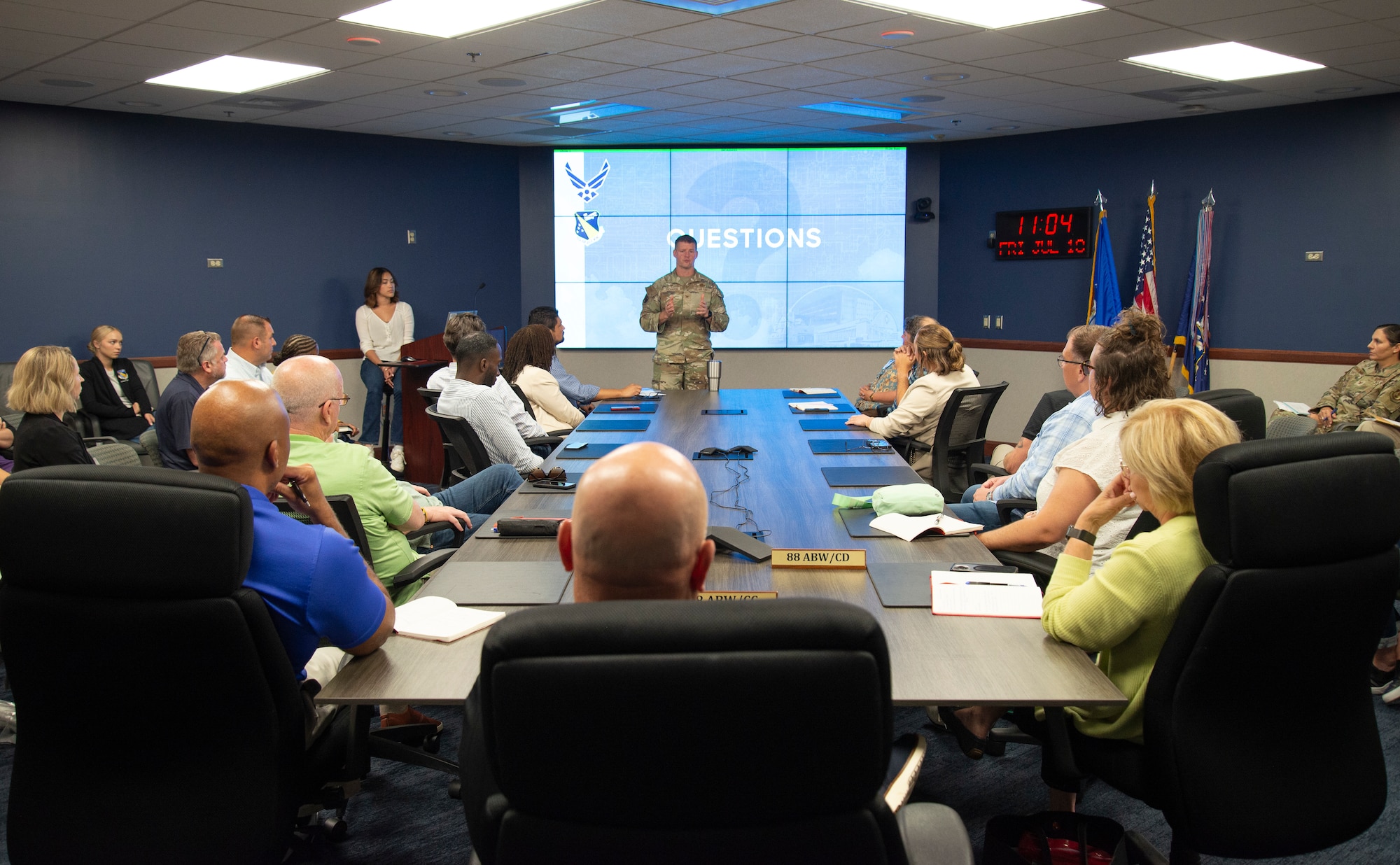 An individual military member talking to a group of individuals while giving a presentation.
